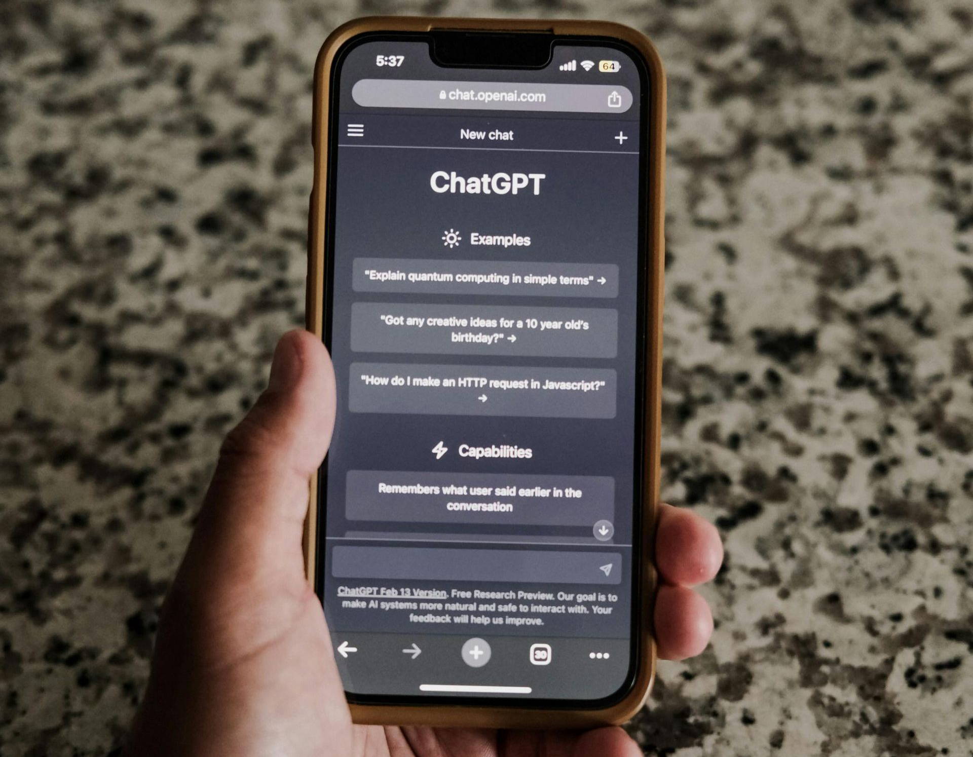 Person's hand holding a phone displaying the ChatGPT interface on a dark background.