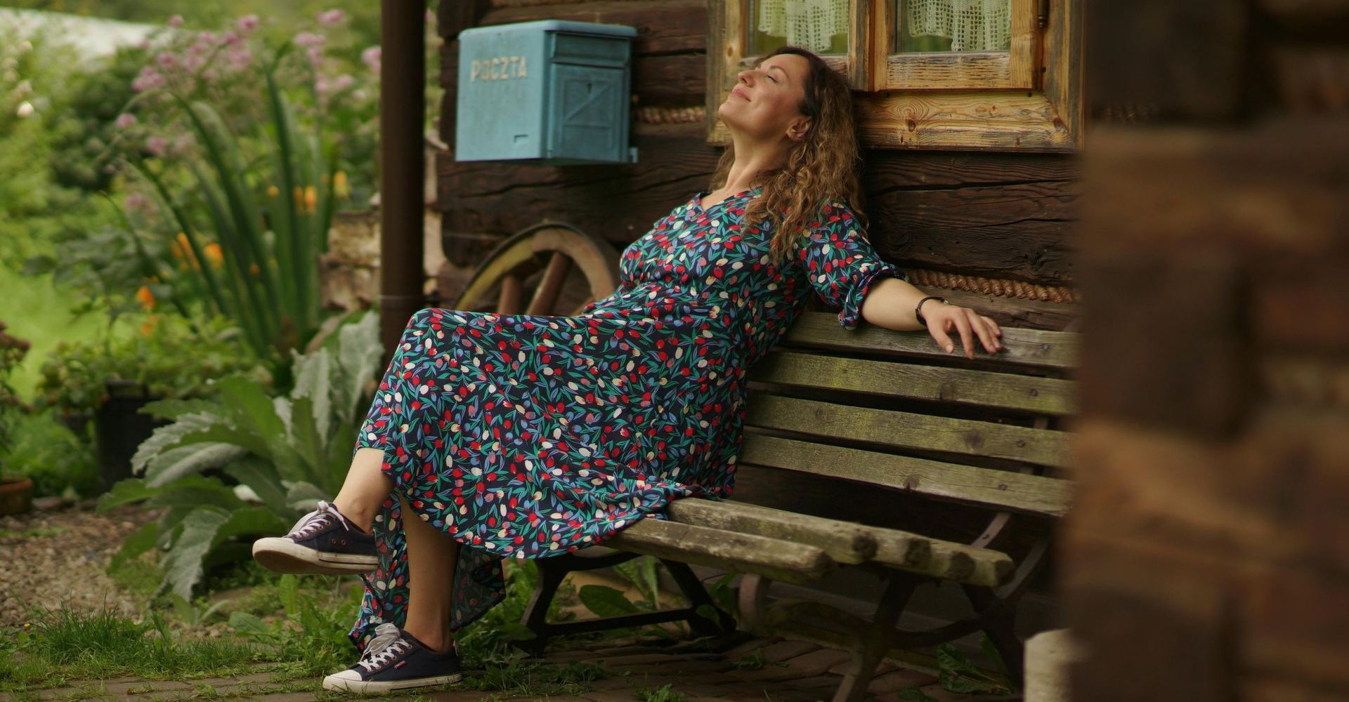 A woman sitting on a bench, outside, smiling in the pleasant Vermont weather.