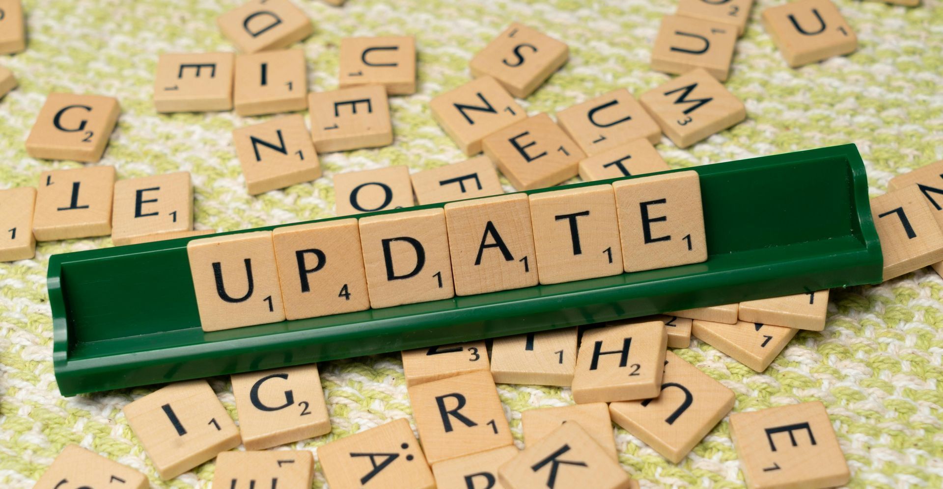 Letter tiles are scattered on a table, with the word, update spelled out on a holder.