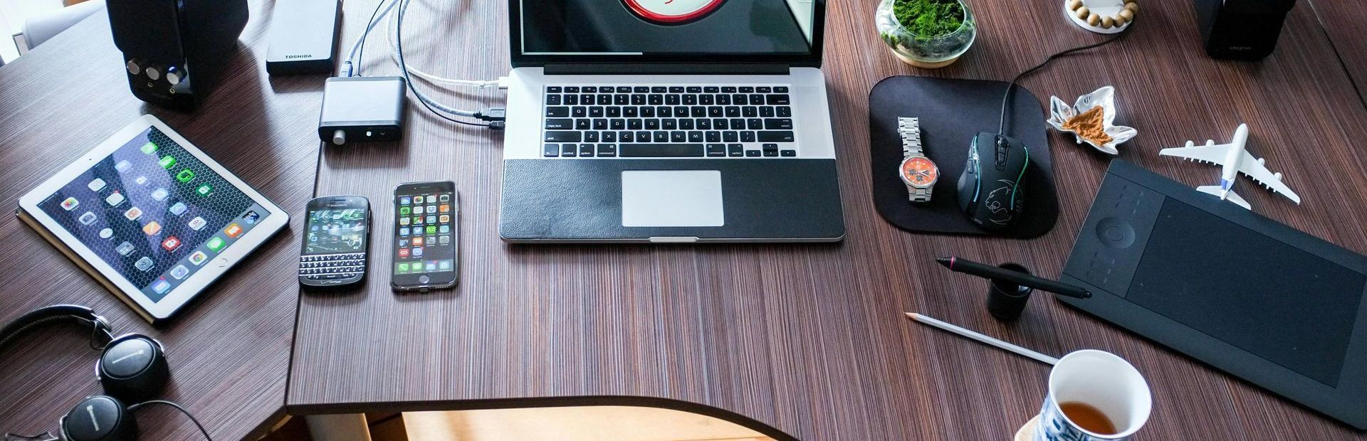 Office desk with multiple forms of technology, Laptop, iPhone, blackberry and ipad.