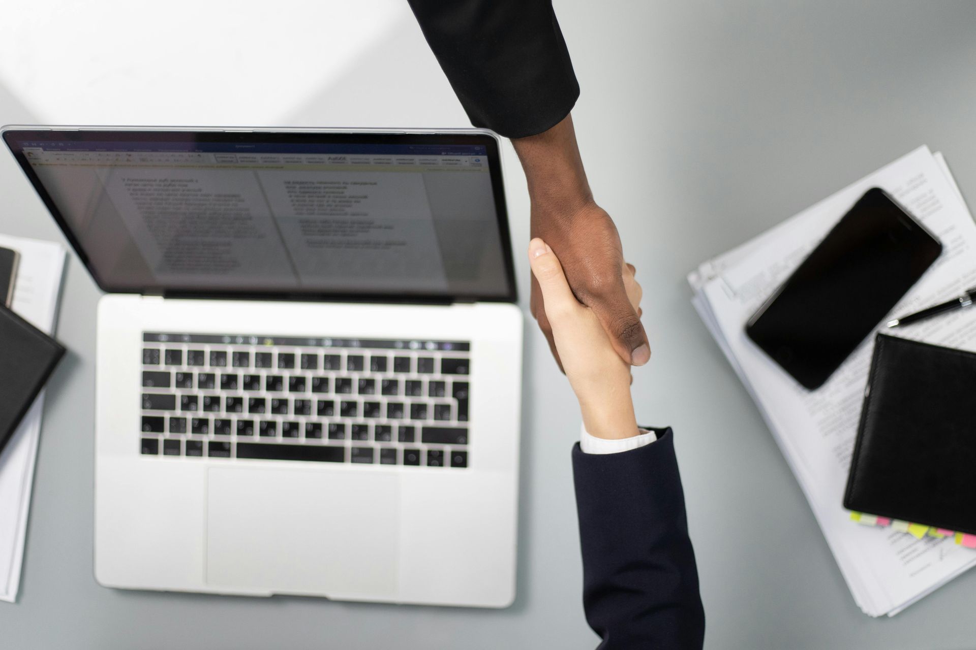 Business handshake beside a laptop representing lead follow-up and customer relationship management.