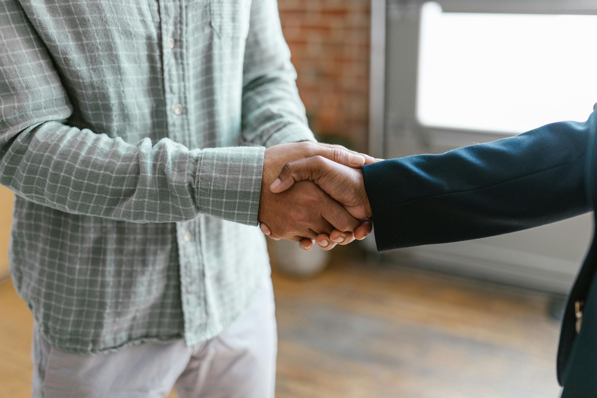 Two professionals shaking hands in an office, representing partnership, collaboration, and trust
