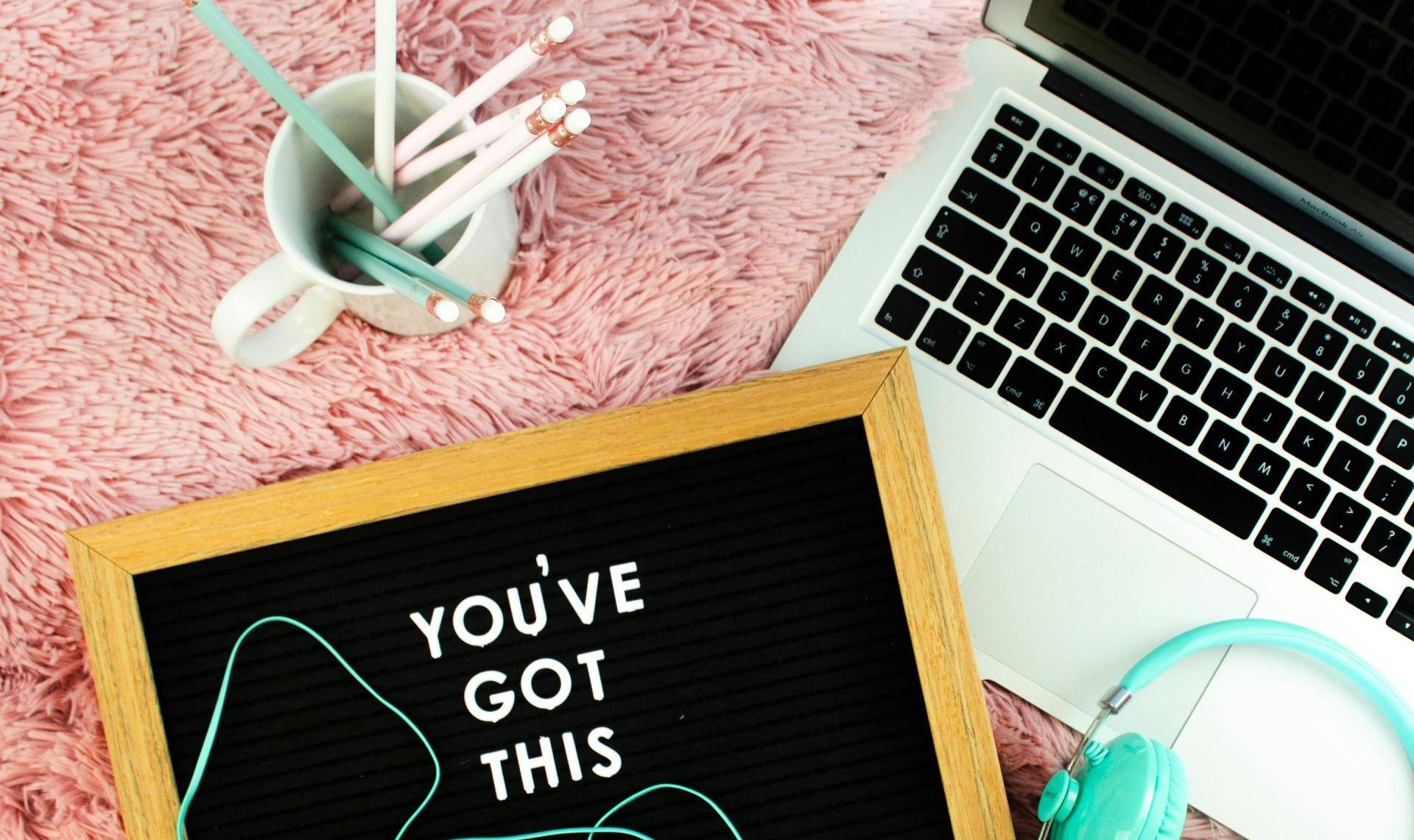 Image on comforter with pencils, laptop and headphones with a sign that says, 