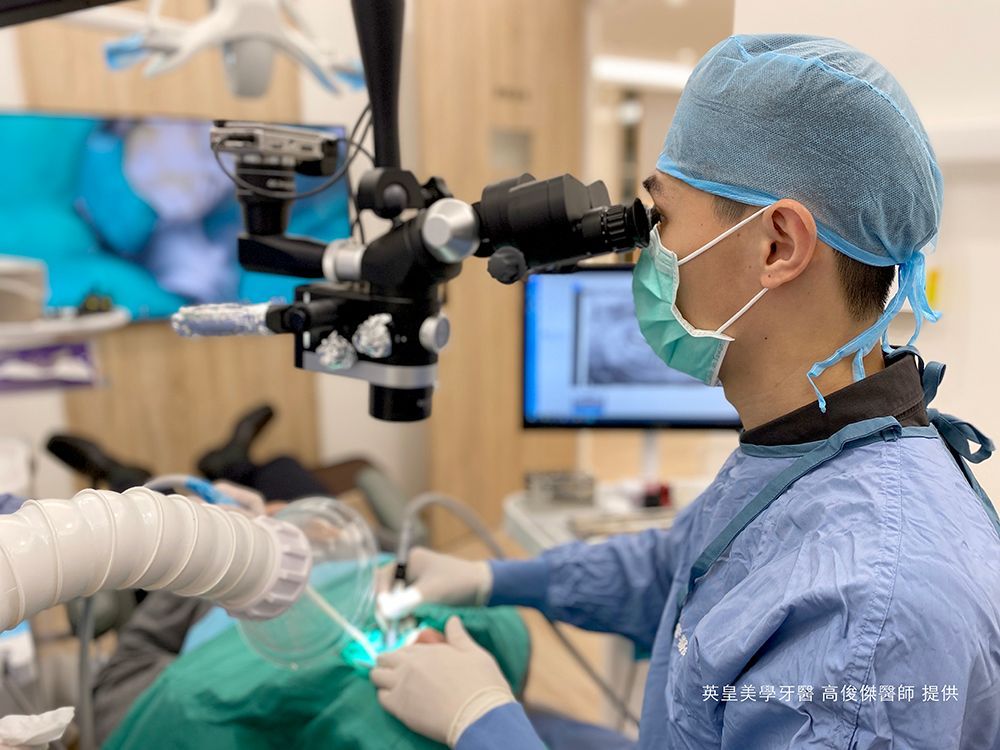 A dentist is using a microscope to look at a patient 's teeth.