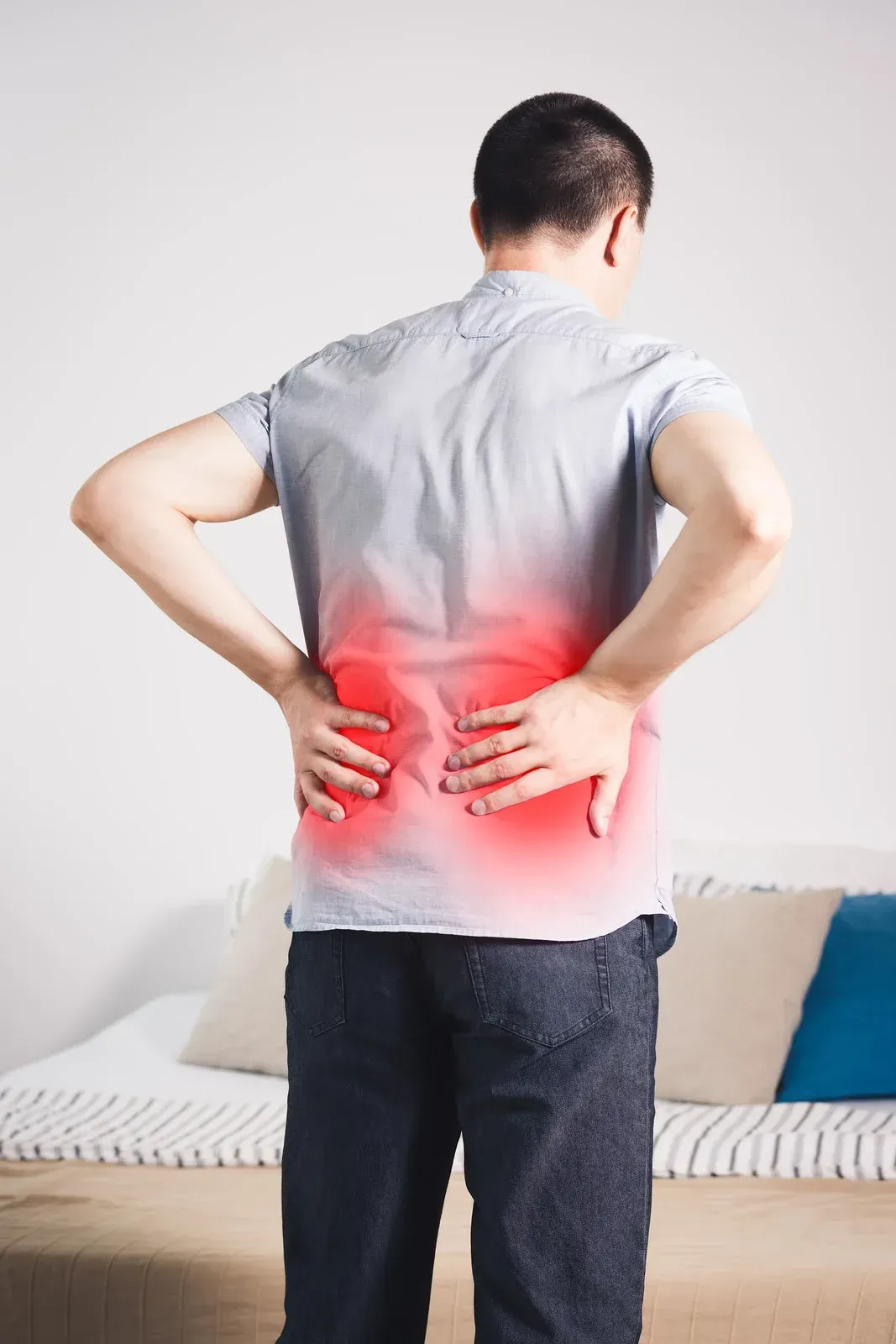 Man with hands on lower back, indicating pain; red glow highlights the area.