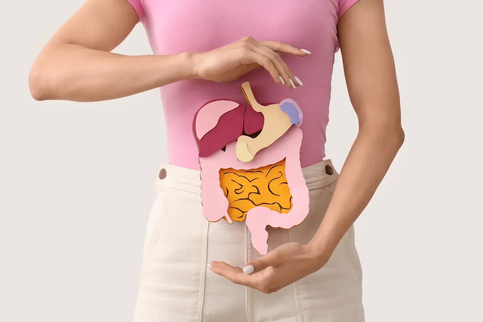 Woman holding a paper cutout of the digestive system.