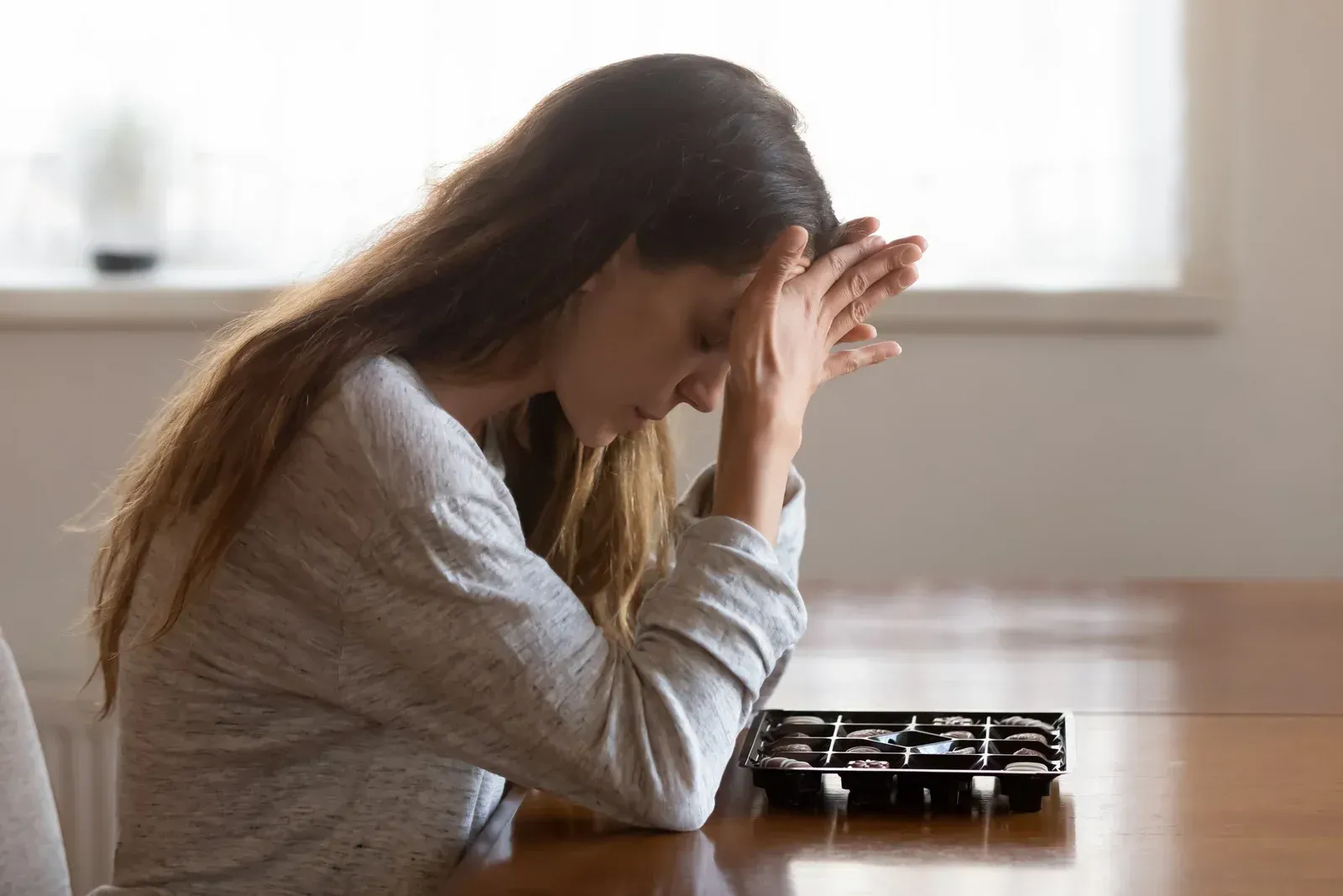 Woman with hands on her face in a library, looking stressed and overwhelmed.