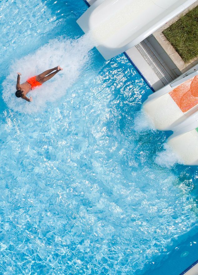 A man is riding down a water slide at a water park.