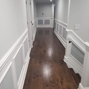 A long hallway with hardwood floors and white trim.