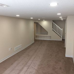 An empty basement with a staircase leading to the second floor.