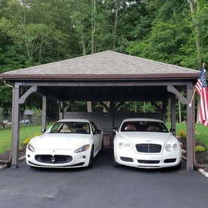 Two white sports cars are parked under a carport.