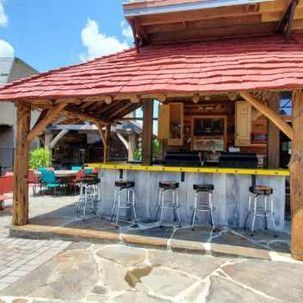 A wooden bar with a red roof and stools underneath it.