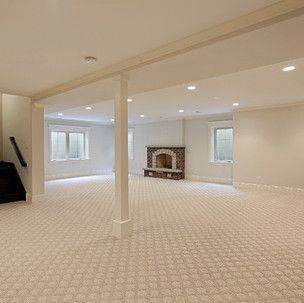 An empty basement with a fireplace and stairs.