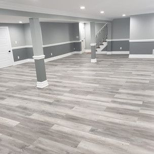 A basement with hardwood floors and gray walls.