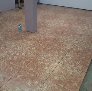 A bottle of water is sitting on a tiled floor next to a pillar.