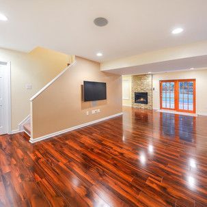 A living room with hardwood floors , a fireplace and a flat screen tv.