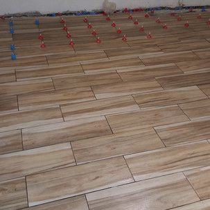 A wooden floor with tiles being installed on it.