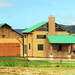 A wooden house with a green roof is sitting in the middle of a grassy field.