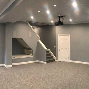 An empty basement with stairs and a projector on the ceiling.