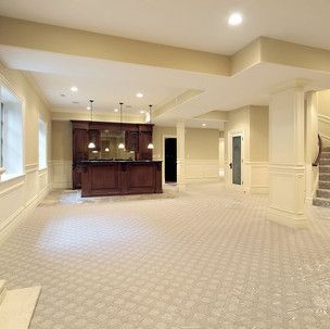 A large empty basement with a bar and stairs.