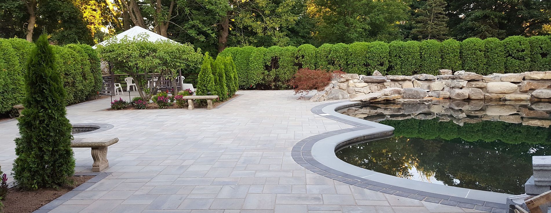 A patio with a pond and a waterfall in the background.