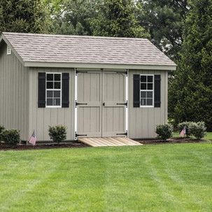 A shed with a ramp leading to it is sitting in the middle of a lush green field.