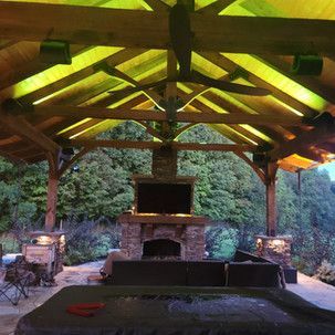 A living room with a fireplace and a television under a wooden roof.
