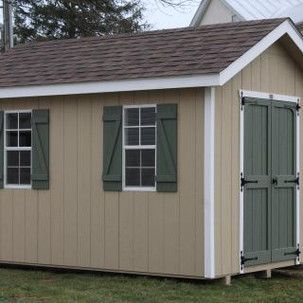 A small shed with green shutters on the windows and doors.