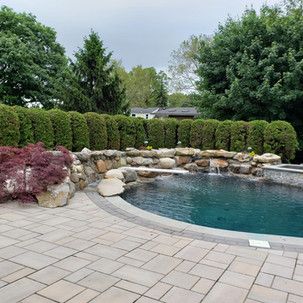 There is a large swimming pool with a waterfall in the backyard.