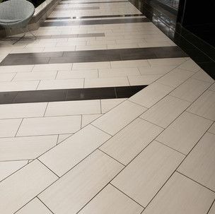 A hallway with white tiles and black stripes on the floor.