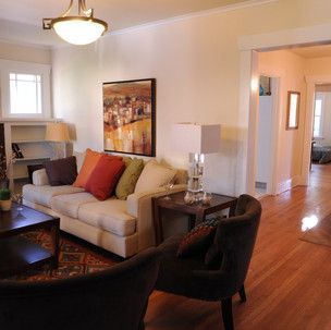 A living room with a couch and chairs and a painting on the wall