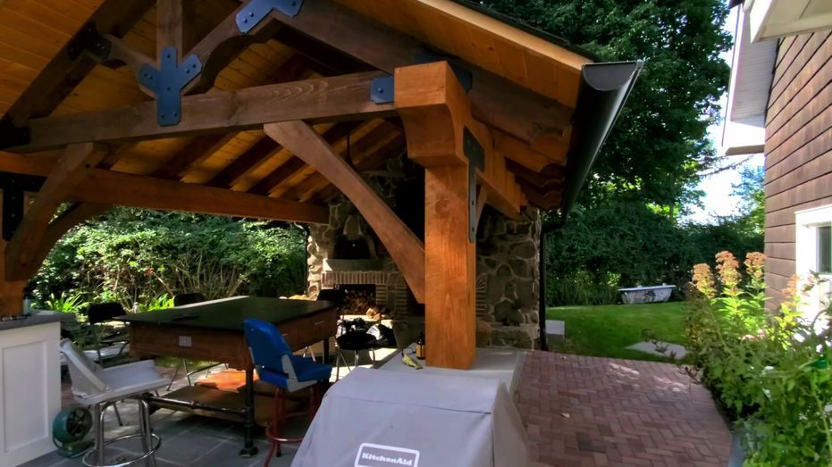 A wooden gazebo with a pool table underneath it