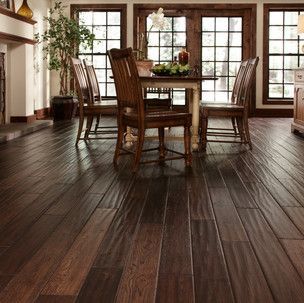 A dining room with a table and chairs on a wooden floor.