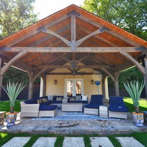 A large pavilion with a wooden roof and a lot of furniture underneath it.