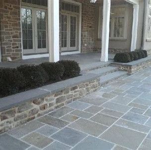 A stone walkway leading to a porch of a house.