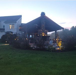 A large house with a gazebo in the backyard at night.