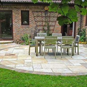 A patio with a table and chairs in front of a brick house.
