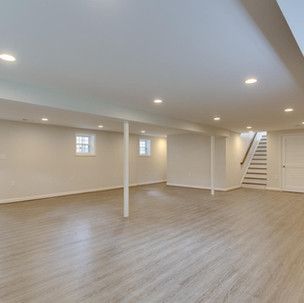 An empty basement with hardwood floors and stairs.