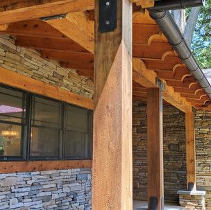 A wooden porch with a stone wall and a roof.