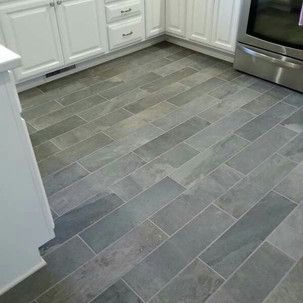 A kitchen with a gray tile floor and white cabinets.
