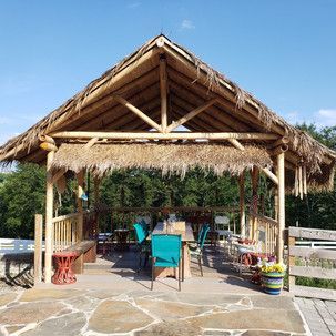 A gazebo with a thatched roof and a table and chairs underneath it.