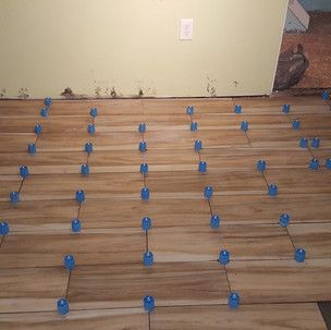 A wooden floor with blue tile spacers on it.