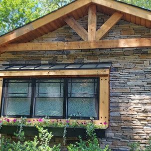 A stone house with a wooden roof and a window with flowers in it.