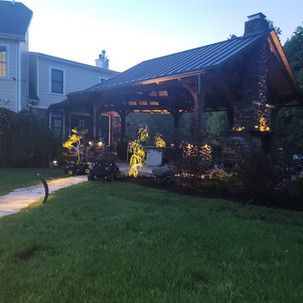 A house with a gazebo in the backyard is lit up at night.