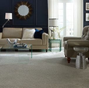A living room with a couch , chair , coffee table and mirror.