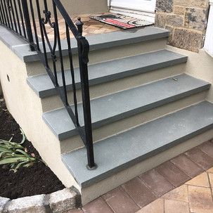 A set of stairs leading up to a house with a wrought iron railing.