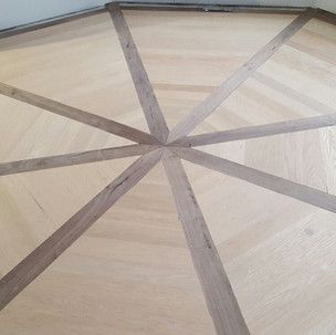 A wooden floor with a pattern of triangles in a circle.