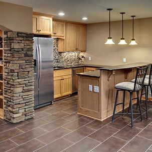 A kitchen with stainless steel appliances , wooden cabinets , a refrigerator and a bar.