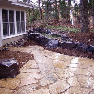 A stone walkway leading to a house in the woods.