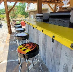 A row of bar stools with flames painted on them are lined up next to a yellow counter.